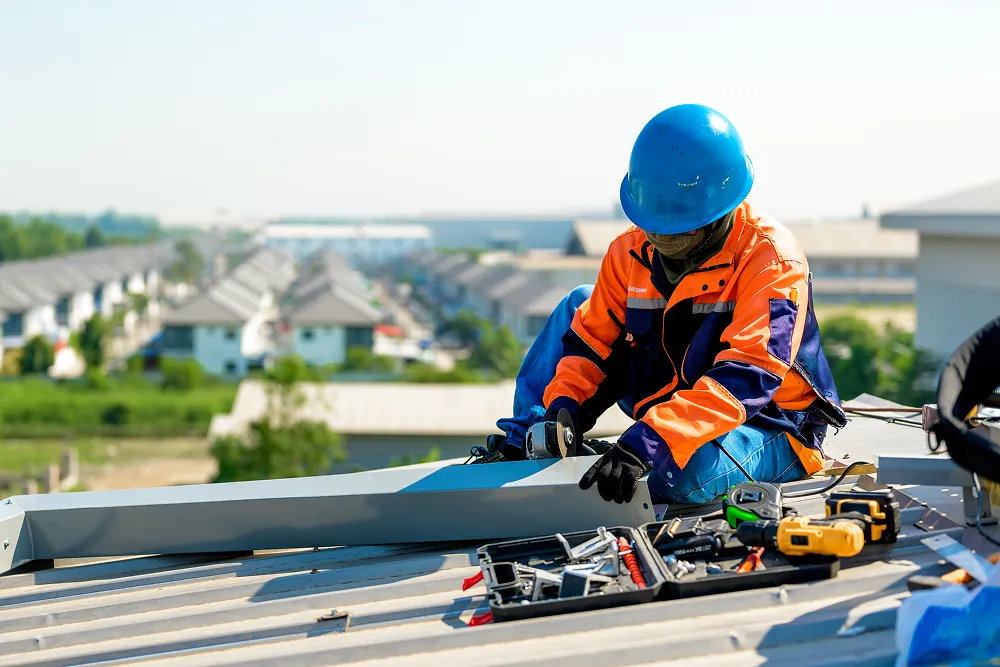 Roofer kneeling on a roof with tools and a camera-ready view of the section being checked